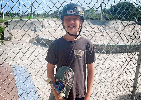 Photo of team rider Tripp Pingston holding skateboard at skatepark